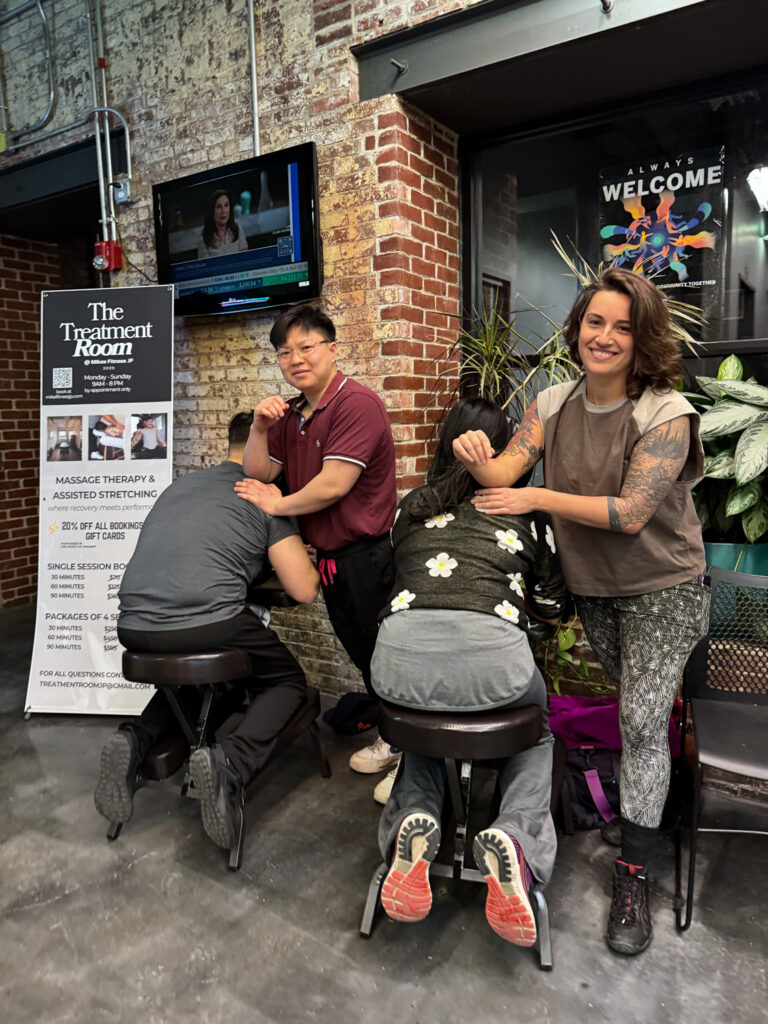 Two Treatment Room therapists giving chair massages in the lobby at Mike's Fitness JP in Jamaica Plain